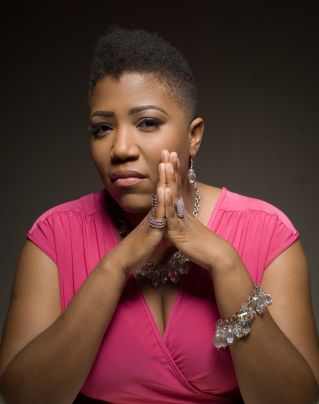 Ebony N. Lea wearing a pink jumper with her hands pressed together wearing jewelry